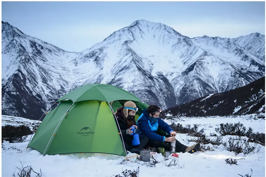 A scene of a tent being set up in the snow with two climbers sitting inside the tent surrounded by snow-covered mountains highlights the tent’s all-season capabilities and its robustness in adverse weather conditions.